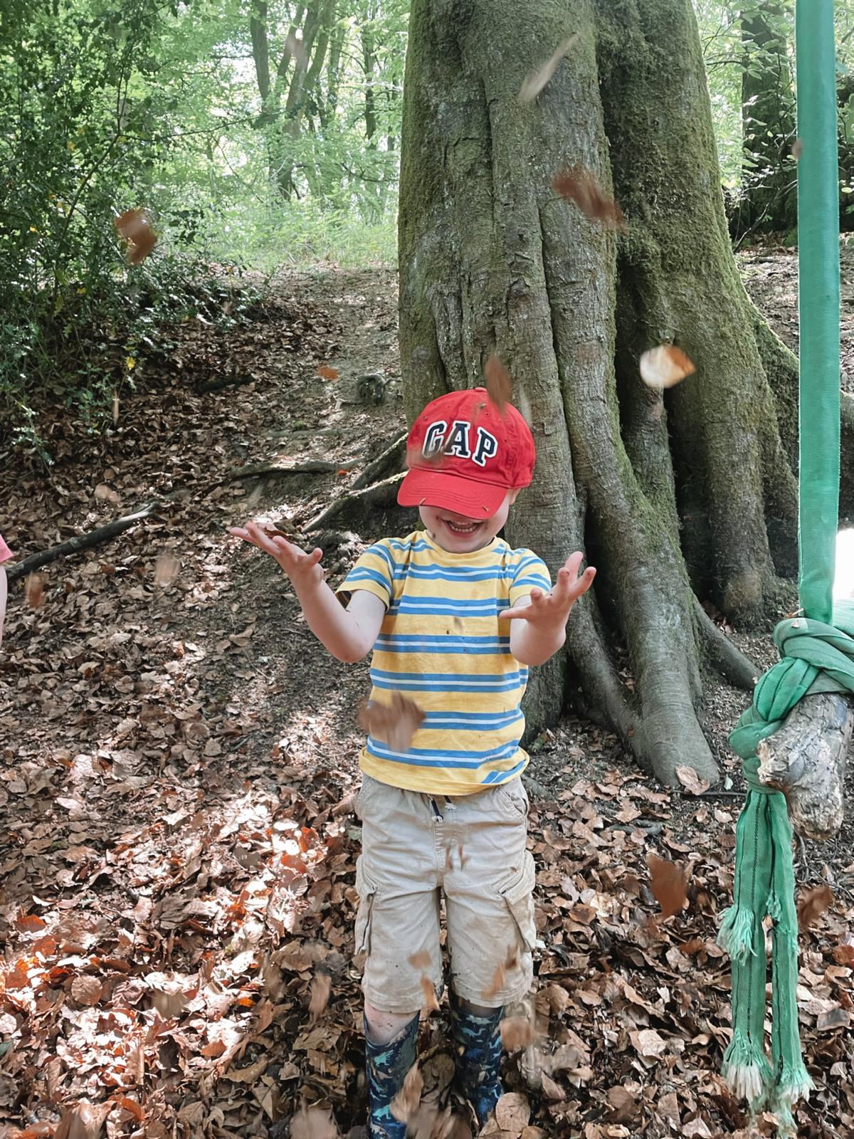 A child playing with fallen leaves